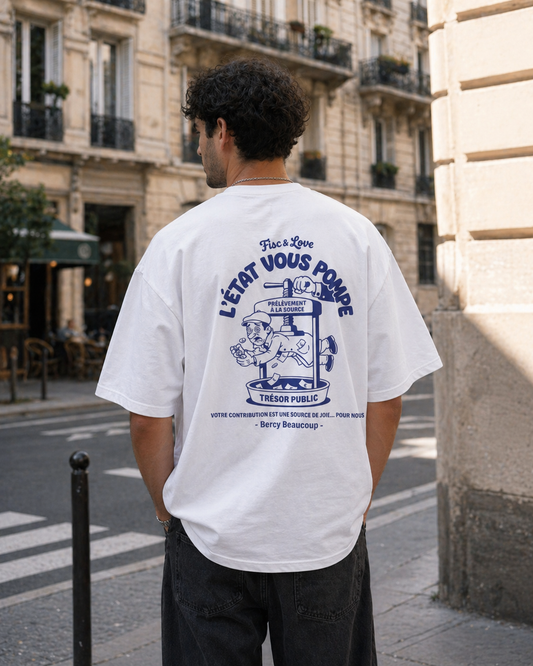 Photographie lifestyle d'un homme de dos dans une rue de Paris, portant un t-shirt blanc oversize avec l'illustration satirique bleue 'L'ÉTAT VOUS POMPE' et 'Bercy Beaucoup'."