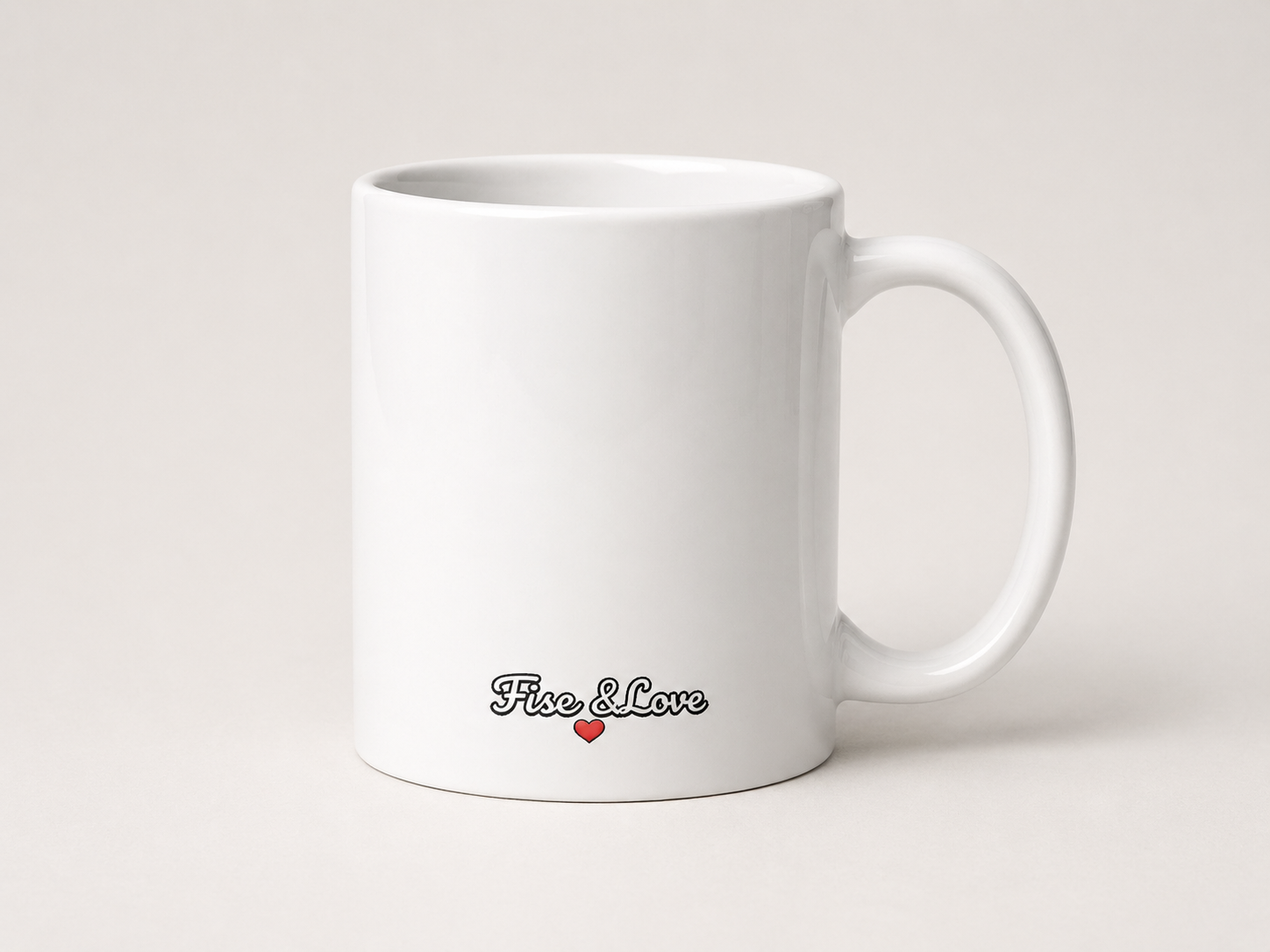 Photographie de trois-quarts d'un mug en céramique blanche posé sur un fond neutre. Le logo « Fisc & Love » est imprimé en bas de la tasse dans une police cursive rétro noire, accompagné d'un petit cœur rouge. L'anse du mug est visible sur la droite, et l'éclairage propre met en avant la brillance de la céramique