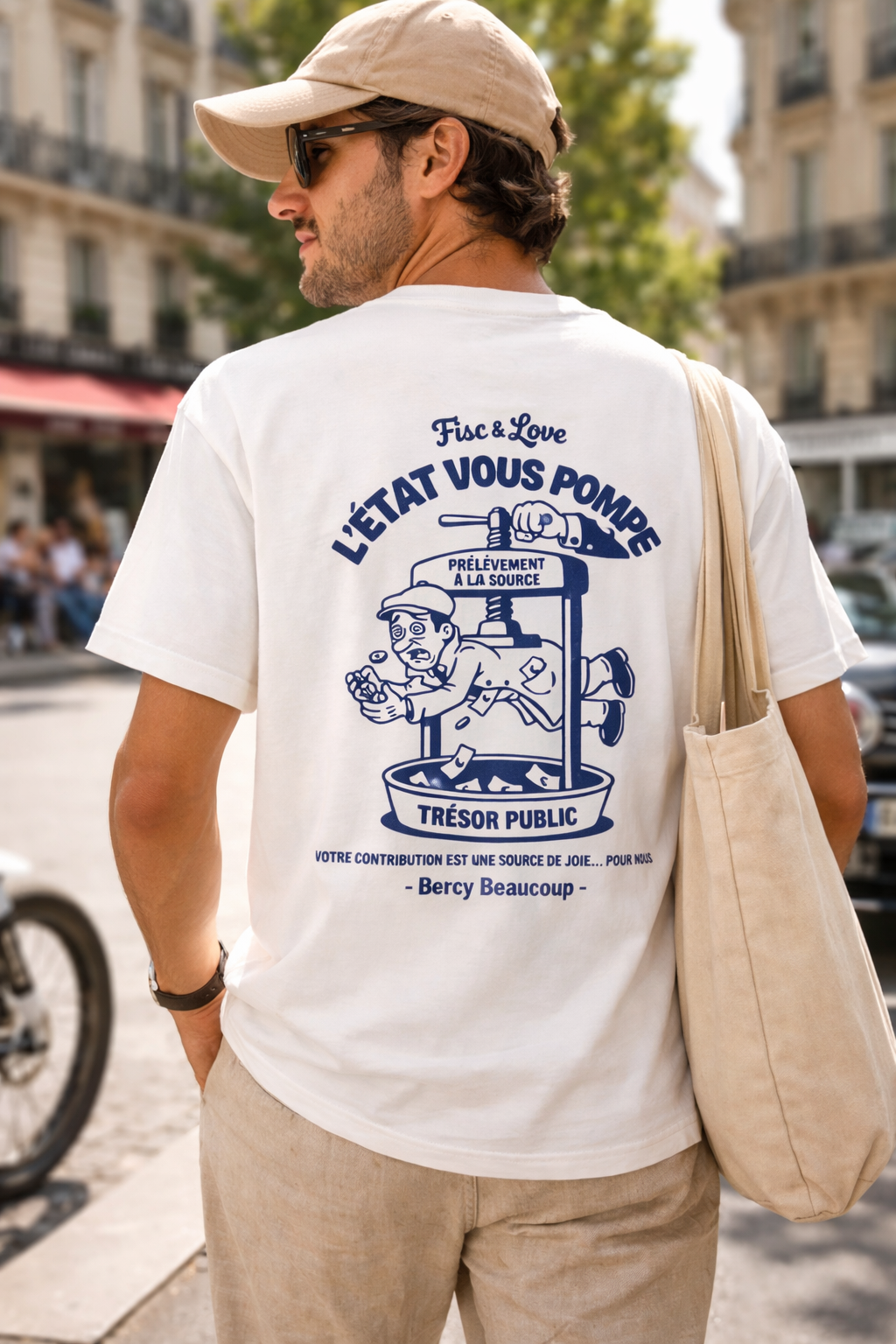 Dos d'un t-shirt blanc porté par un homme, affichant une illustration humoristique bleue sur la fiscalité française avec l'inscription "L'État vous pompe" et un personnage écrasé dans un pressoir marqué "Trésor Public".