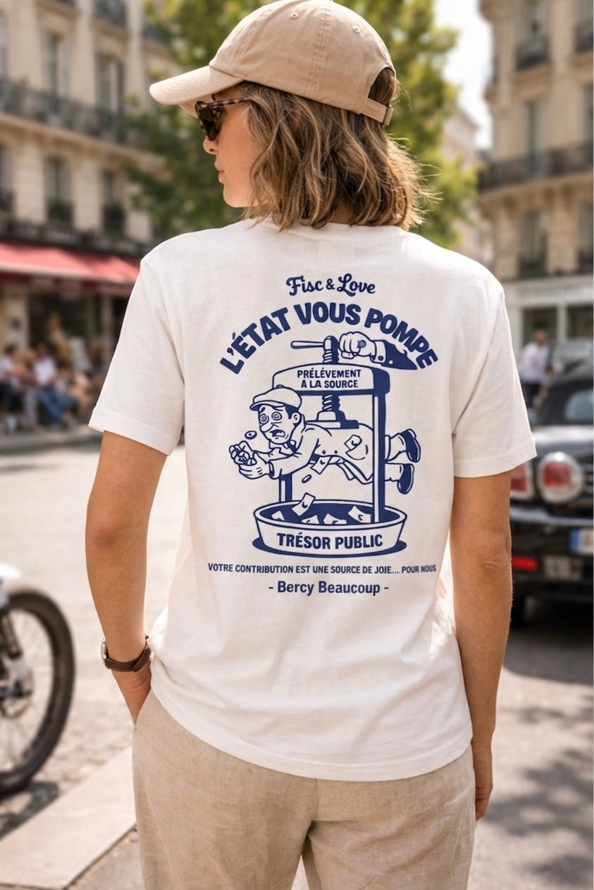 Vue de dos d'une femme portant un t-shirt blanc et une casquette beige, affichant l'illustration humoristique "L'État vous pompe" avec un personnage dans un pressoir marqué "Trésor Public" dans une rue de Paris.
Pourquoi cette version :