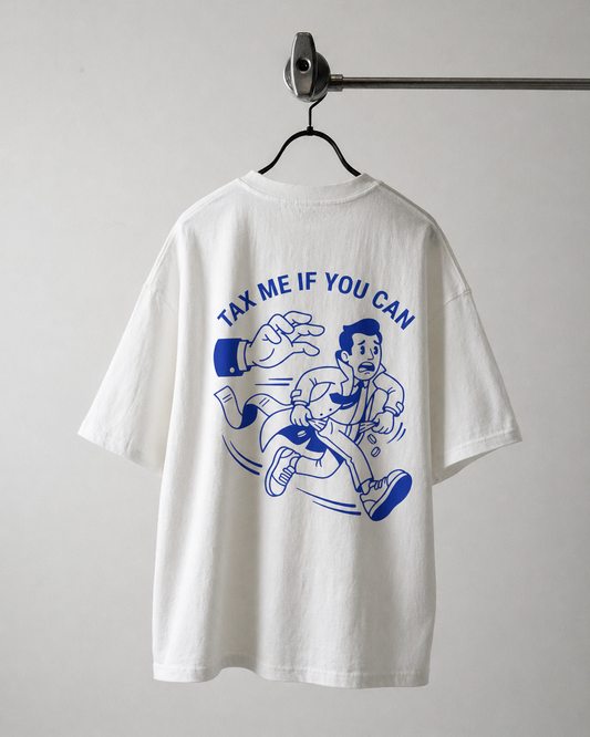 "Dos d'un t-shirt blanc oversize avec une illustration bleue de style cartoon montrant un homme en costume poursuivi par une main géante, avec le texte 'TAX ME IF YOU CAN