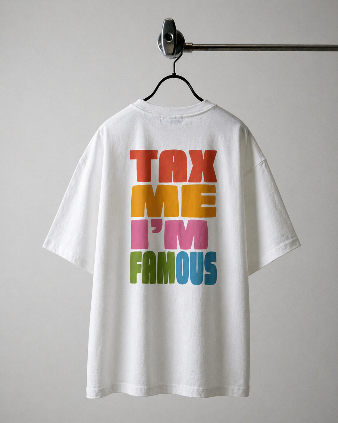 Dos d'un t-shirt blanc oversize avec l'inscription 'TAX ME I'M FAMOUS' imprimée en lettres colorées (rouge, orange, rose, vert et bleu)
