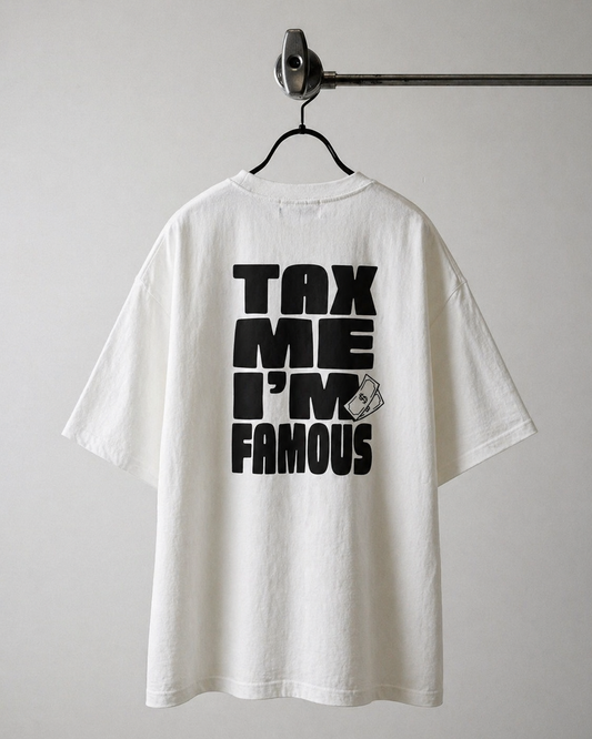"Dos d'un t-shirt oversize blanc avec l'inscription 'TAX ME I'M FAMOUS' imprimée en grosses lettres noires et une petite illustration de billet de banque."